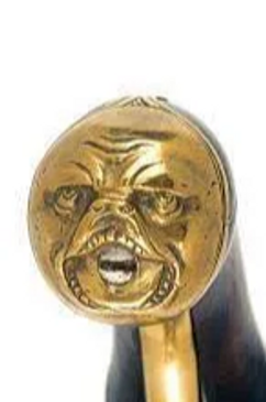 A close-up of a brass or gold-colored decorative item with a grotesque face.
