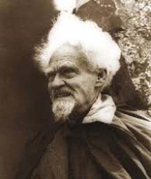 An elderly man with white hair and beard in a cloak.