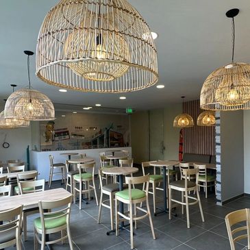 Modern dining area with light wooden chairs and woven pendant lights.