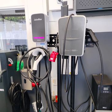 Electric vehicle charging stations with cables and connectors in an indoor setting.
