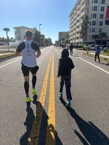 Man and child walking on a sunny city street during an outdoor event.