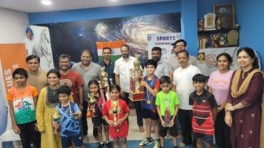 Group photo with children holding trophies and adults smiling.