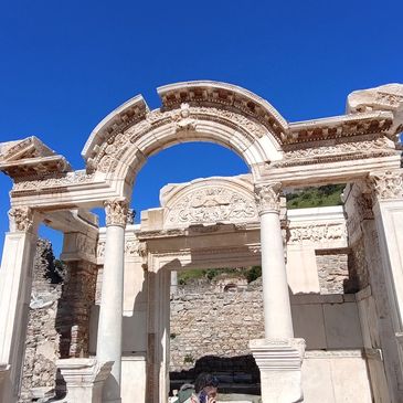 Ancient stone archway ruins under a clear blue sky.
