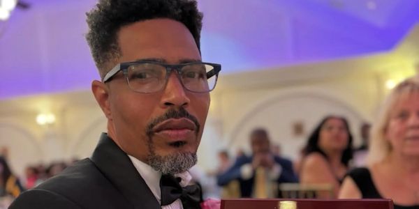 Man in tuxedo and glasses at a formal event.