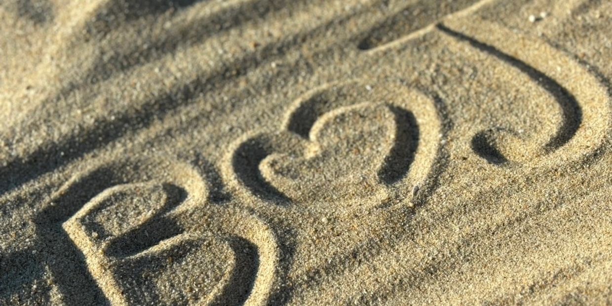 The phrase "I ♥ U" carved in the sand with shadows.