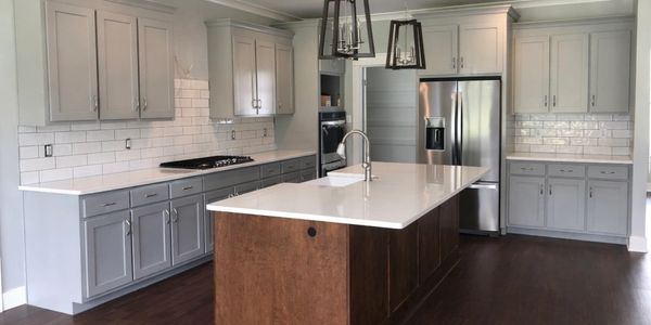 Modern kitchen with gray cabinets, white countertops, and a wooden island.