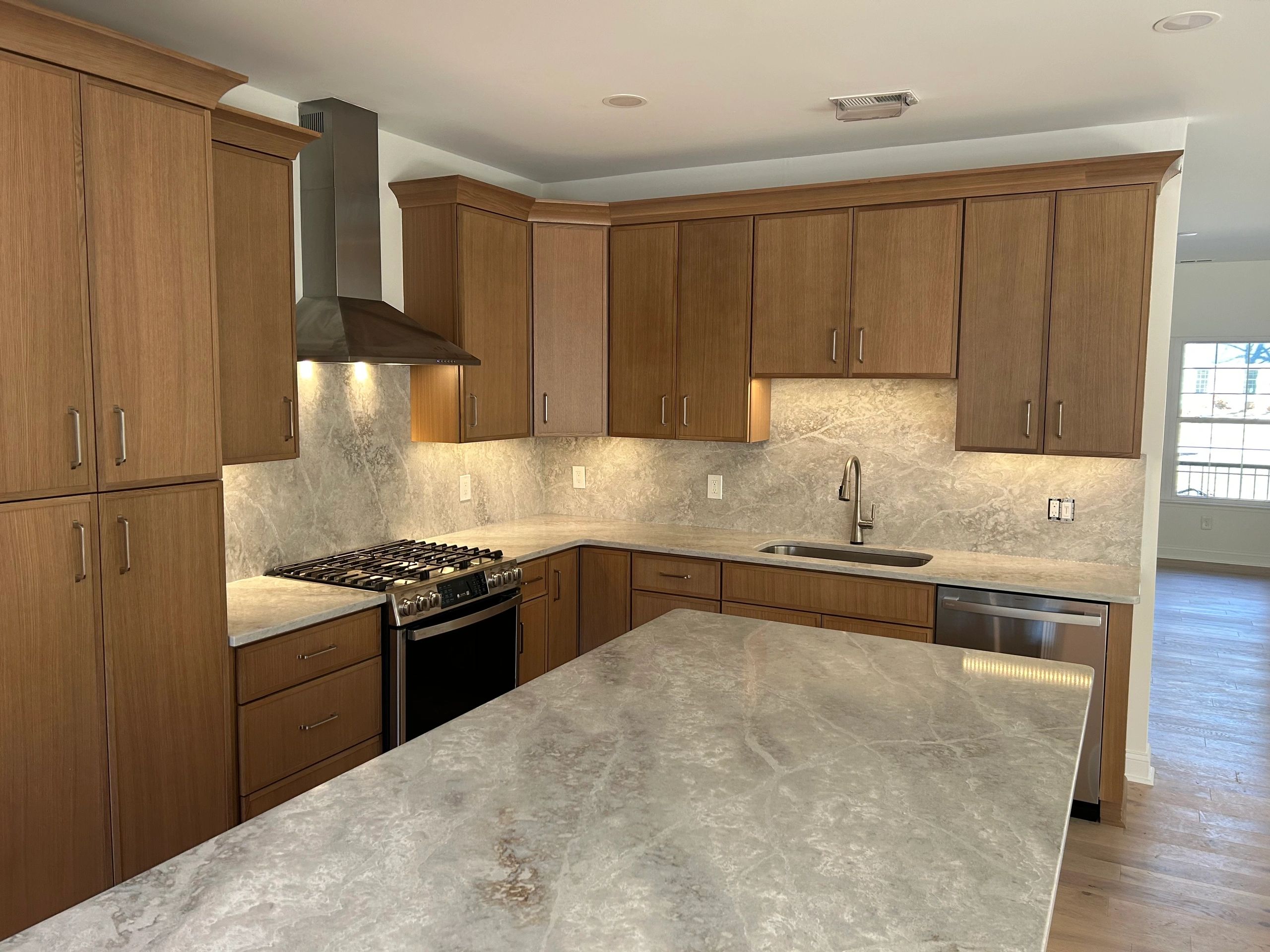 Modern kitchen with wooden cabinets and marble countertops.