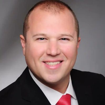 Smiling man in a suit with a red tie.