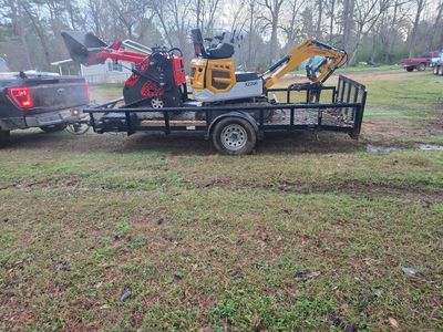A trailer carrying a mini excavator and a log splitter attached to a truck.