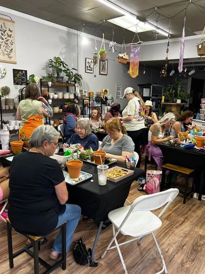 People engaged in a group craft activity with plants in a cozy indoor setting.