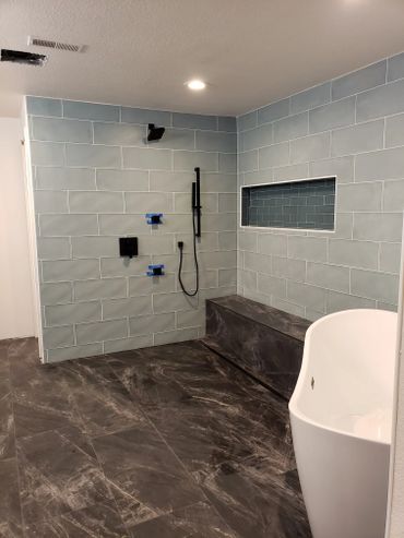 Modern bathroom with blue tiled walls and dark marble floor.