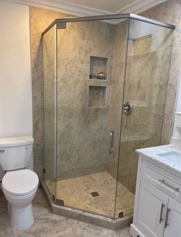 Modern bathroom with glass shower, toilet, and white vanity.