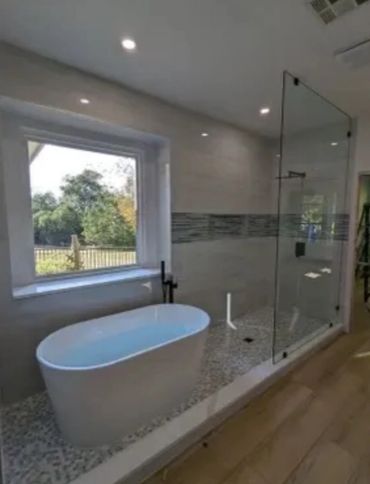 Modern bathroom with freestanding tub and glass shower enclosure.
