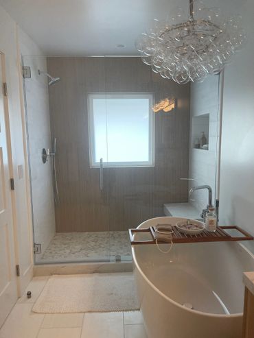 Modern bathroom remodel with freestanding tub and glass shower enclosure.