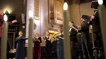 Choir performing in a grand hall with lit candles in foreground.