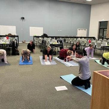 A group yoga class practicing cat-cow pose indoors.