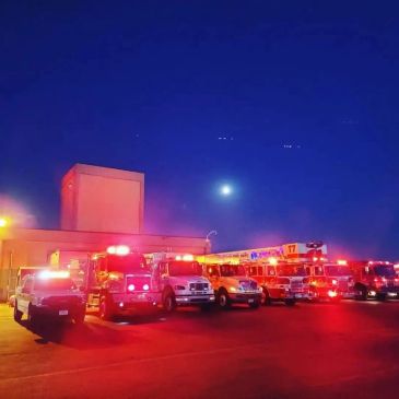Fire trucks lined up at night with their lights flashing.