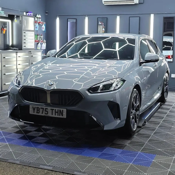 A sleek silver BMW parked indoors with reflective ceiling lights.