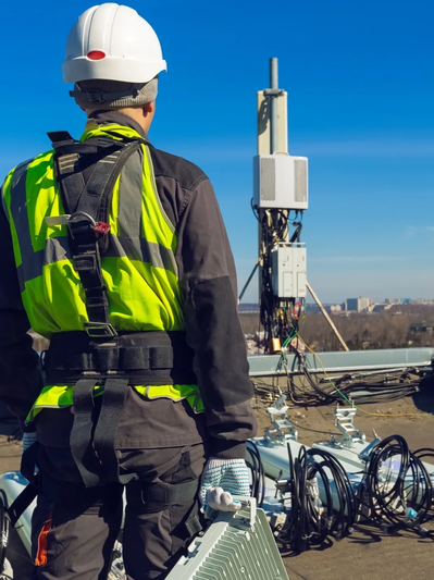 Technician inspecting a telecom antenna on a rooftop.