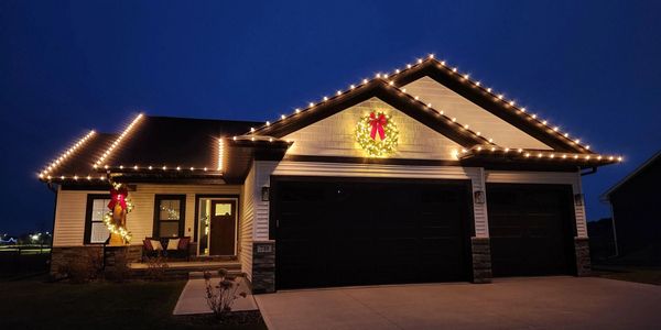 House decorated with Christmas lights and wreaths at night.