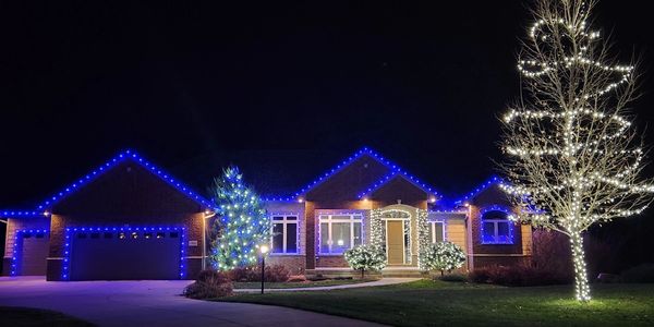 House decorated with blue and white Christmas lights at night.