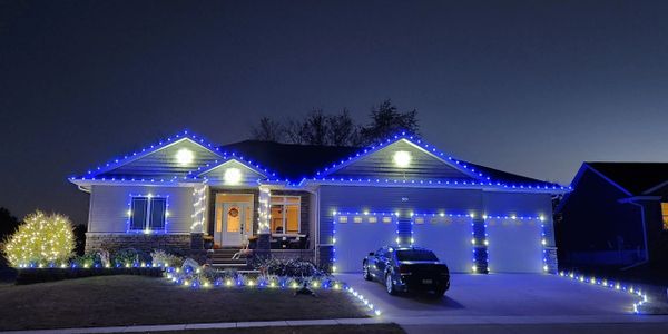 House decorated with blue and white Christmas lights at night.