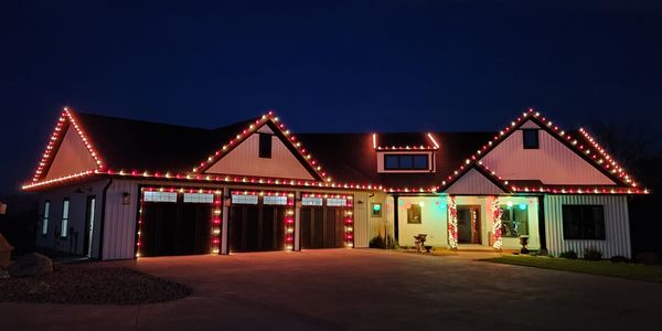 House decorated with colorful Christmas lights along the roof and pillars at night.