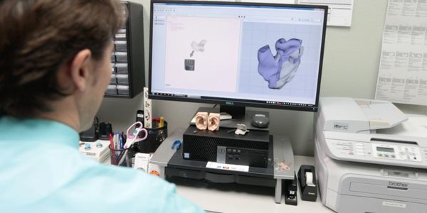 Dr. Asay, Audiolgist, scans a 3D file of a patient's impression for manufacturing.