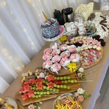 Elegant dessert table with cakes, chocolates, and fruit skewers.