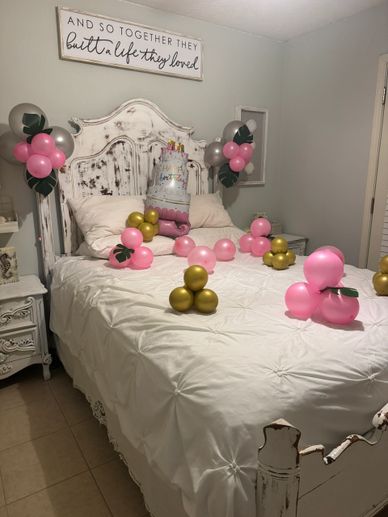 Bedroom decorated with pink and gold balloons and a birthday cake on the bed.