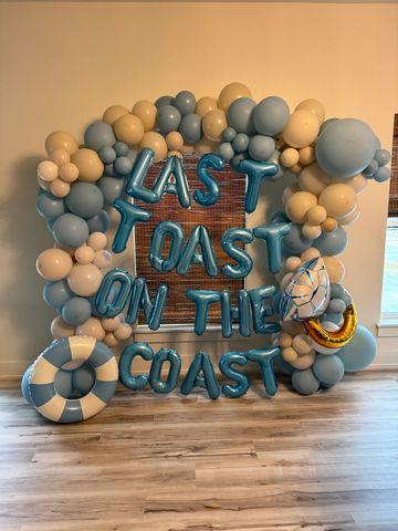 Balloon arrangement reads 'Last Toast on the Coast' with coastal-themed decorations.