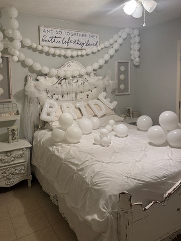 White bridal-themed bedroom decorated with balloons and a 'BRIDE' sign.