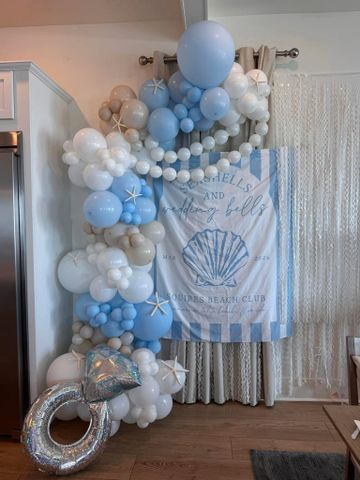 Blue and white balloon arch with starfish and a beach-themed backdrop.