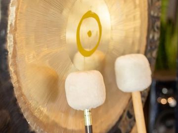 Close-up of a golden gong with two mallets.