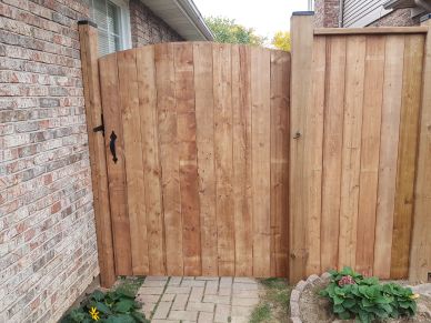 Wooden gate and fence beside brick house.