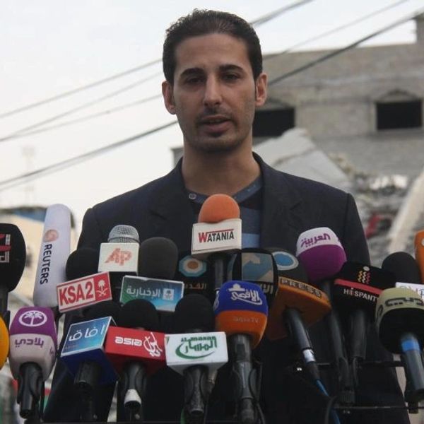 A man speaks at a press conference with many microphones in front of him.