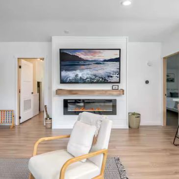 Modern living room with fireplace and ocean view artwork.