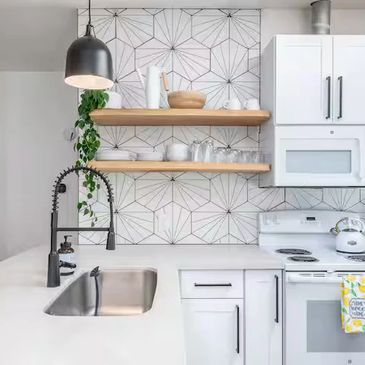 Modern kitchen with white cabinets and geometric backsplash.