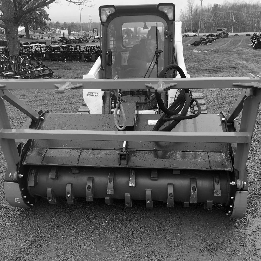 Heavy machinery with a front attachment for ground work on a gravel lot.