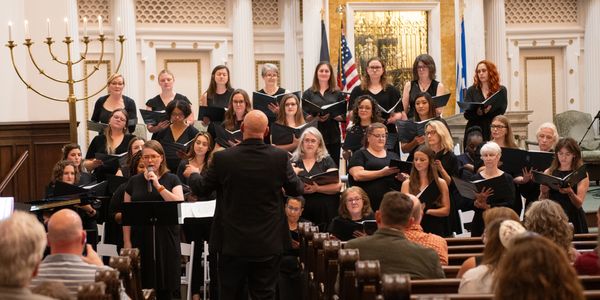 Choir singing under a conductor in a synagogue.