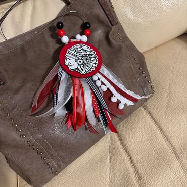 Brown handbag adorned with a colorful Native American-inspired keychain charm.