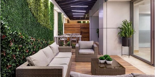 Modern outdoor patio with wicker furniture and green wall accents.