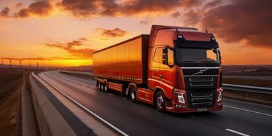 Red Volvo truck driving on highway at sunset.