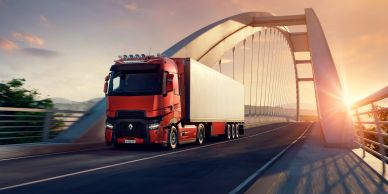 A red truck drives on a bridge at sunset.