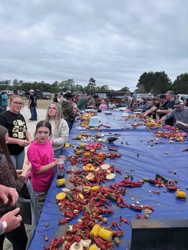 Guests gather along a long table filled with crawfish, corn, and vegetables at the 2026 Doyle Boil.