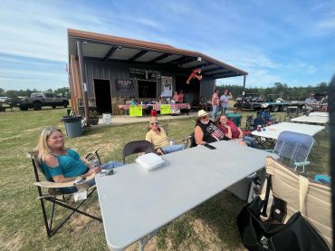Guests gather at a table beside the event barn at the 2023 Doyle Boil.
