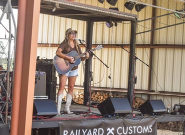 A singer plays acoustic guitar on the stage at the 2025 Doyle Boil.
