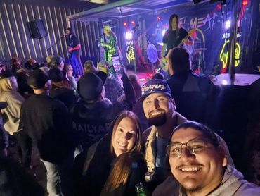 Three smiling guests with the concert crowd and illuminated stage behind them at the 2026 Doyle Boil