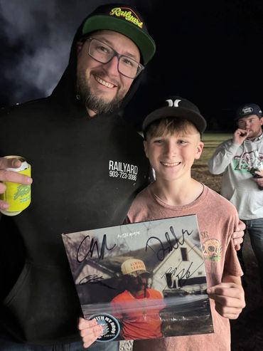 A father and son hold a signed Austin Meade album at the 2026 Doyle Boil.