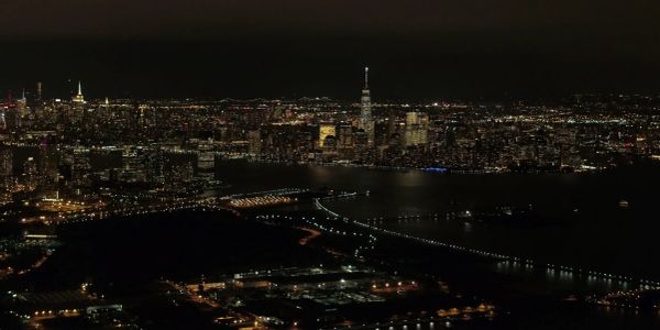 Nighttime skyline of a city with illuminated buildings and a river.